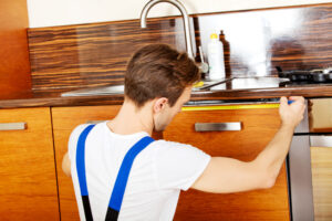 professional renovator measures kitchen cabinets