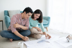 young couple sitting on floor looking at home renovation plans
