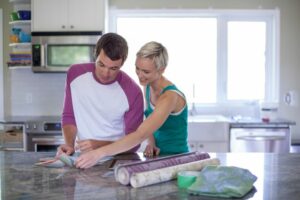 Couple looking at paint and wallpaper swatches in kitchen