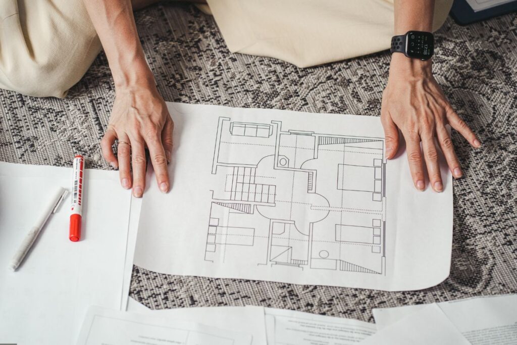 woman looks at home design plans laid out on the floor